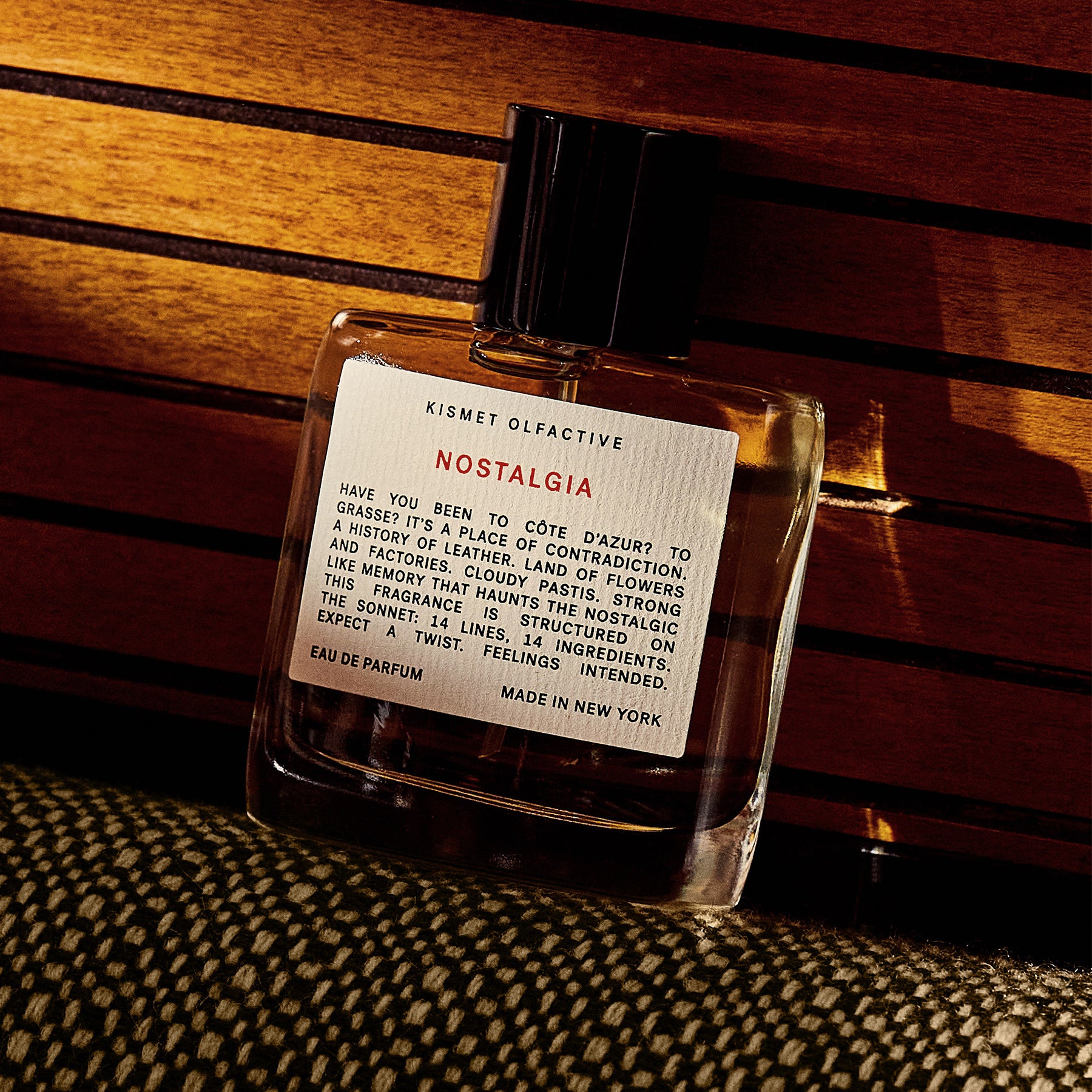 perfume bottle with label that says "nostalgia" against wood background and moody lighting