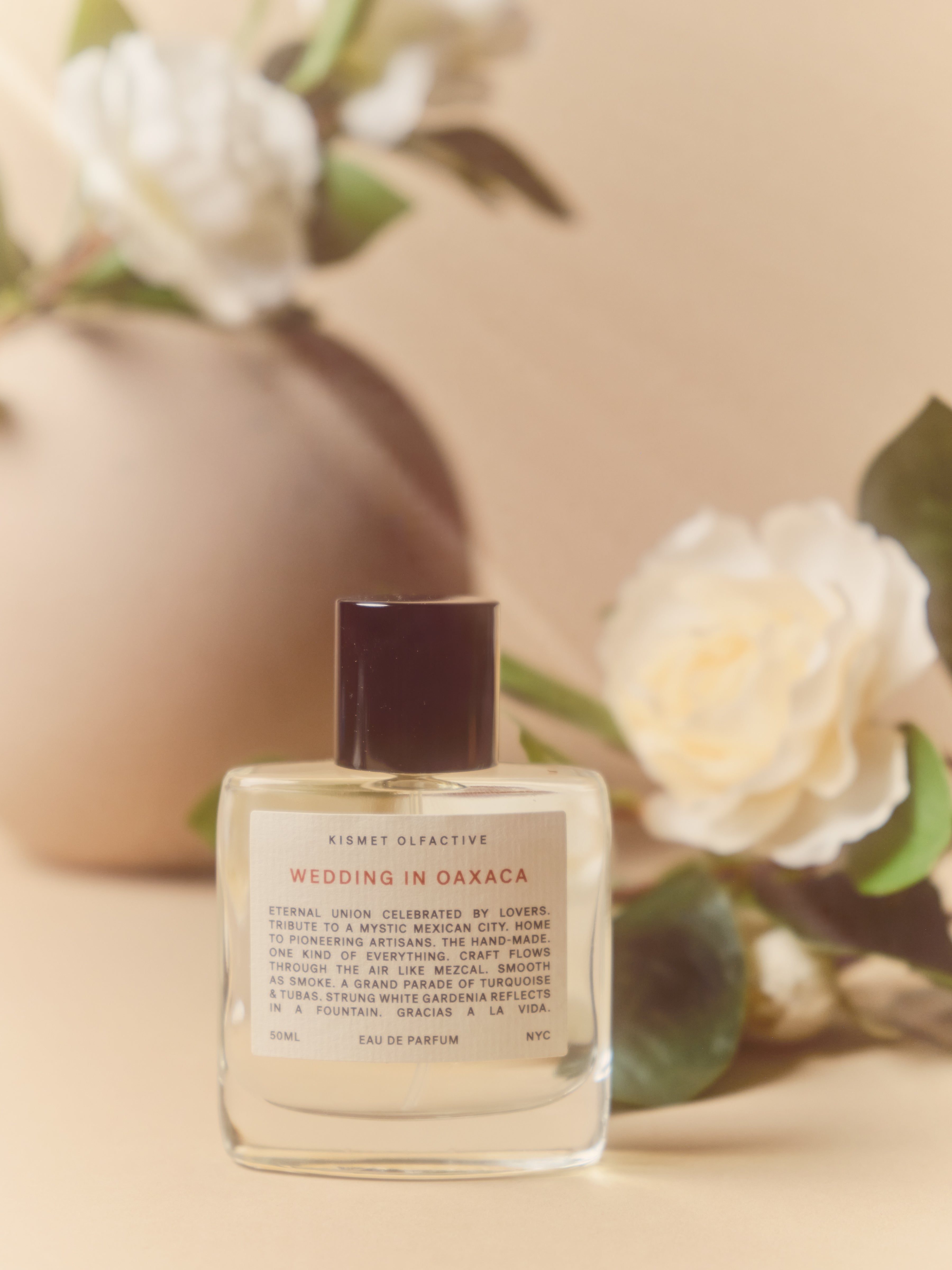 perfume bottle with label that says "wedding in oaxaca" and white flowers in the background