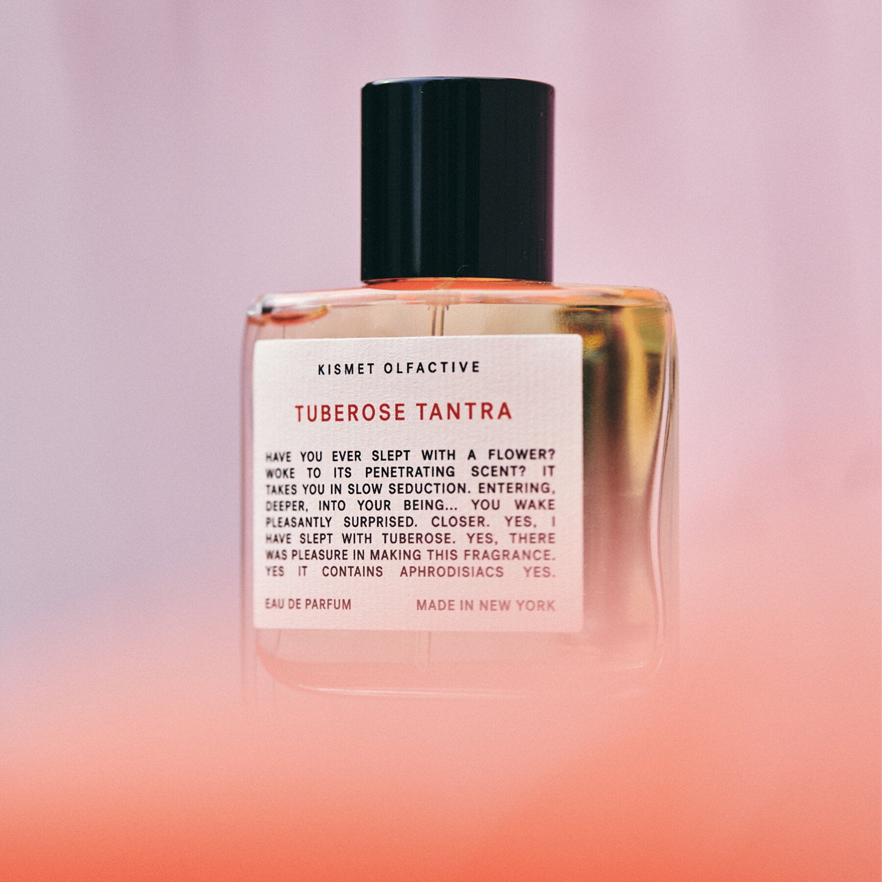 perfume bottle with label that says "tuberose tantra" and a pink gradient background