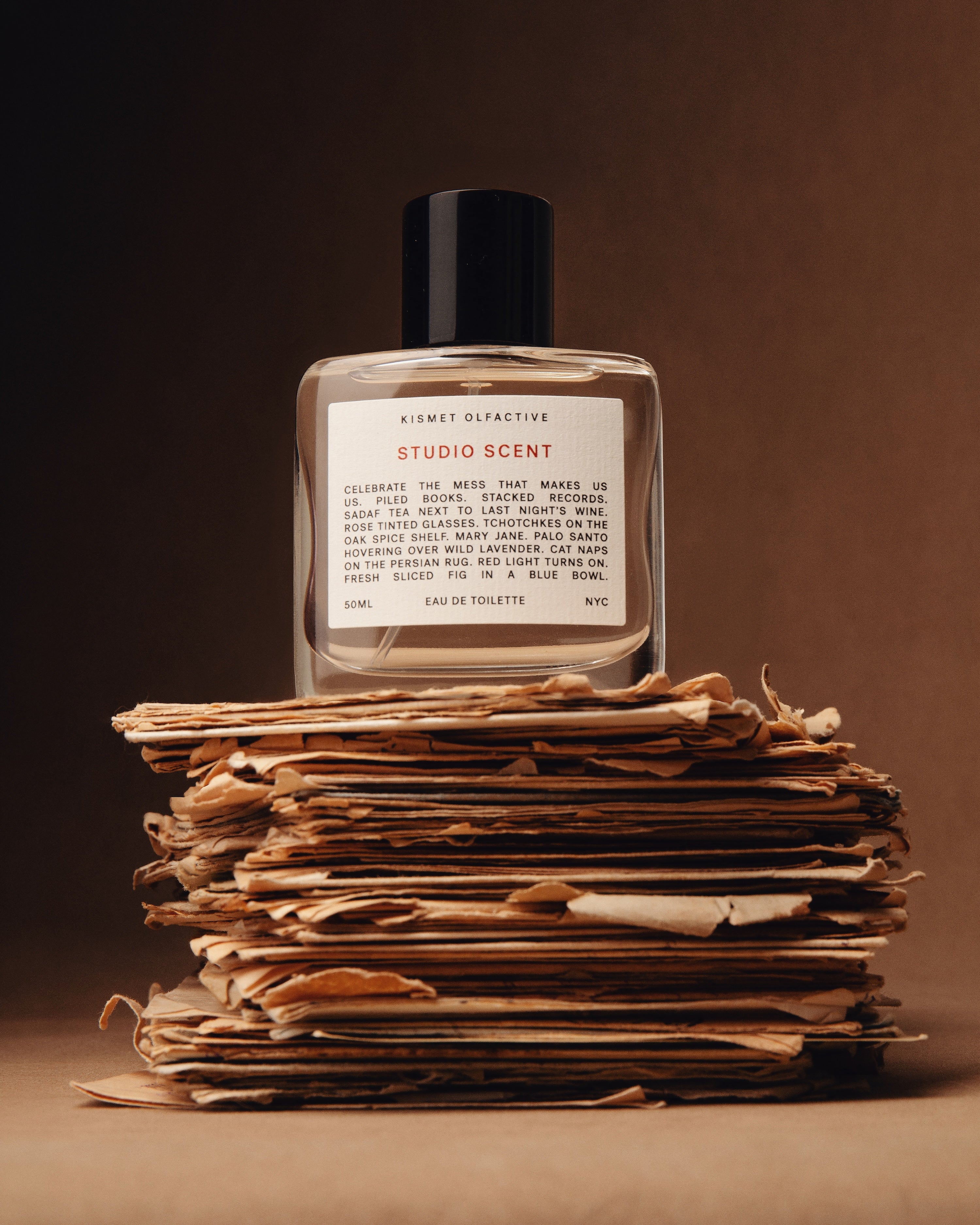 Studio Scent Perfume Bottle on top of old letters against a brown backdrop