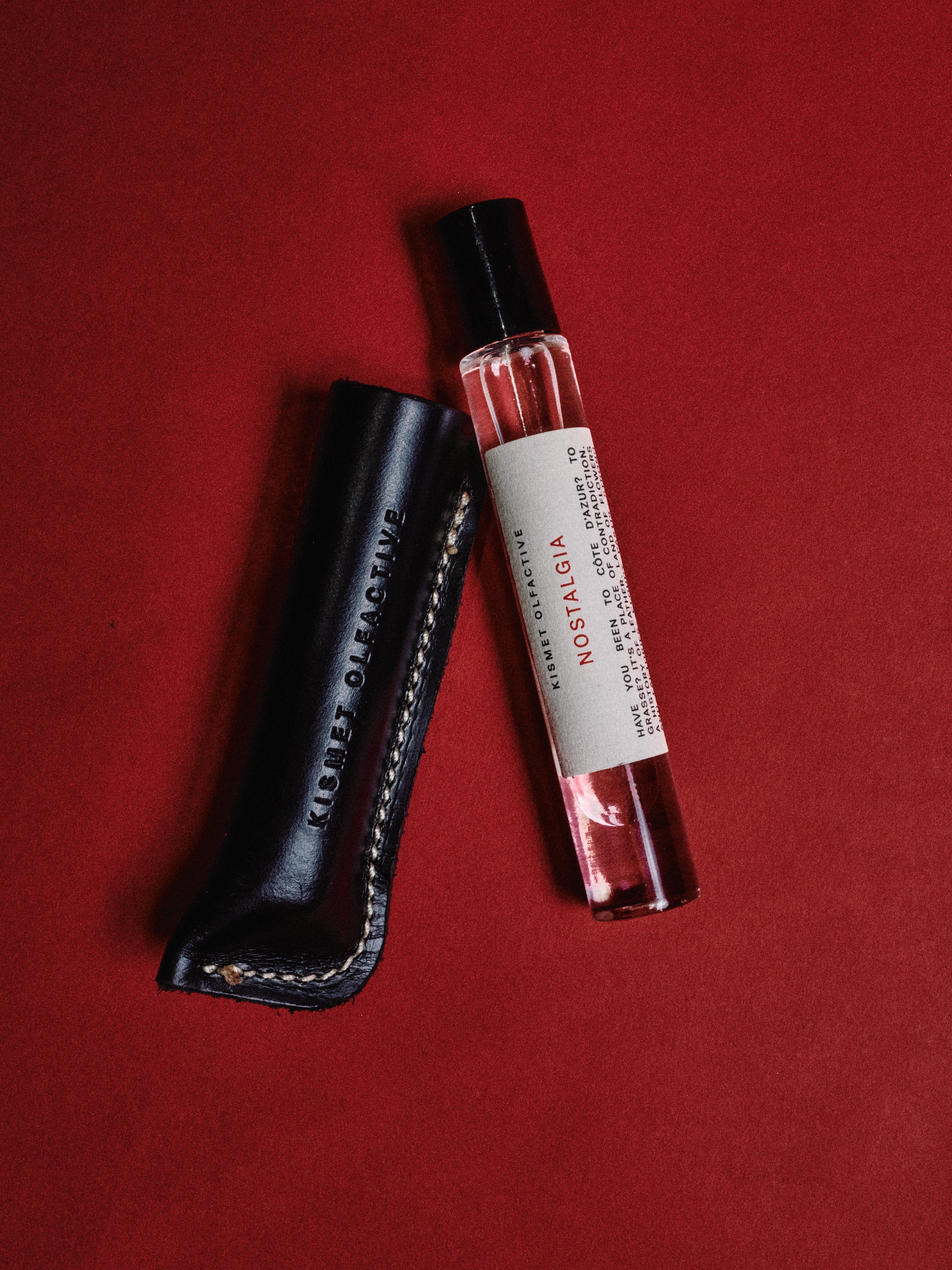 a 10ml bottle of Nostalgia Perfume  with a leather case on a red background