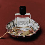 Perfume bottle labeled 'Nymphaéas' on a decorative tray with gold accents against a red background