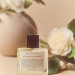 perfume bottle with label that says "wedding in oaxaca" and white flowers in the background