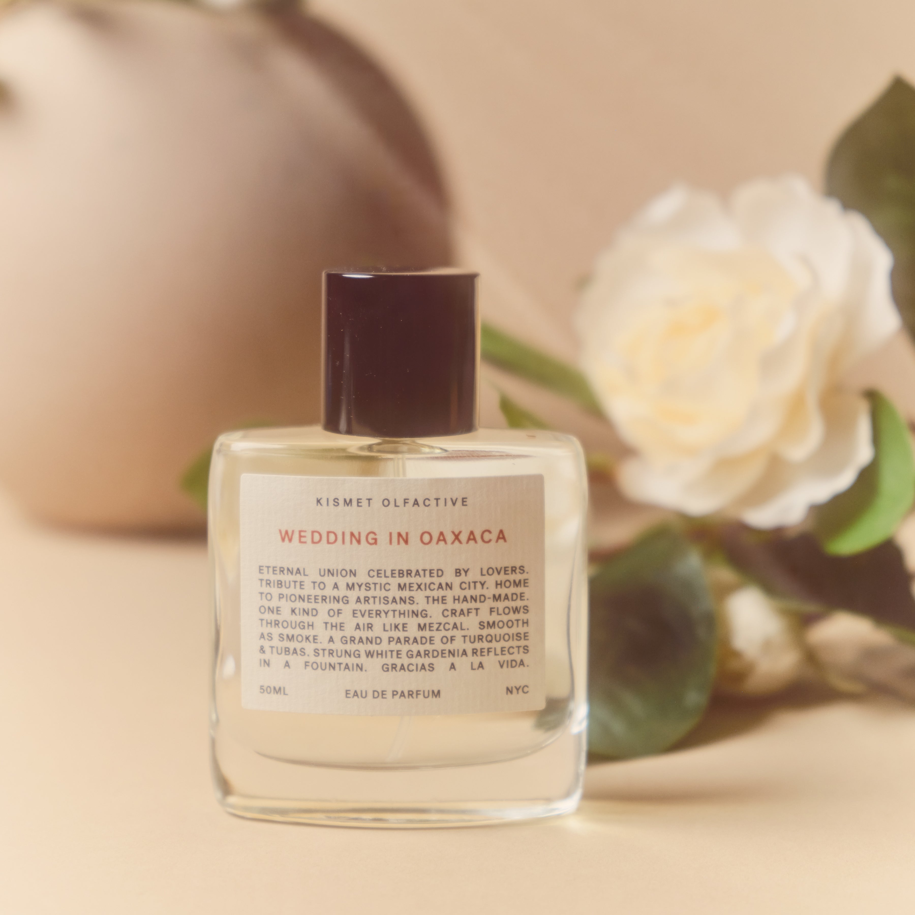 perfume bottle with label that says "wedding in oaxaca" and white flowers in the background